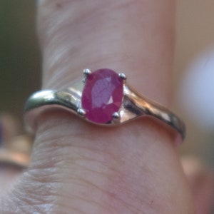 Puede incluir: Un anillo de plata con una piedra preciosa ovalada de color rosa.