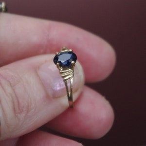 May include: A gold ring with a dark blue oval-shaped gemstone.
