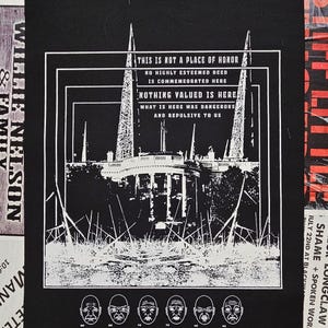 Op de afbeelding: Zwart-wit grafische patch met de tekst: "THIS IS NOT A PLACE OF HONOR." De afbeelding toont een gebouw met twee hoge structuren aan weerszijden. Hieronder zes gestileerde gezichten met verschillende uitdrukkingen. De patch is omgeven door andere gedrukte materialen.