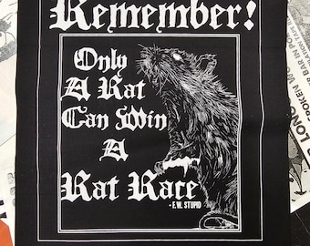 May include: Black square graphic with white text and a detailed illustration of a rat. The text reads "Remember! Only A Kat Can Win A Kat Race - F.W. STUPID". The design is reminiscent of a punk rock aesthetic.