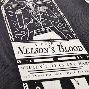 May include: Black tote bag with a white graphic of a skeleton in a naval uniform. The text "A DROP OF NELSON'S BLOOD" is displayed below the illustration, along with other text. The bag is made of a woven fabric.