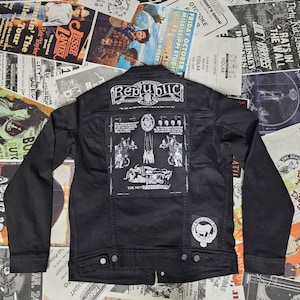 May include: Black denim jacket with patches and the word "Republic" on the back. The jacket has a button-up front, two chest pockets, and two side pockets. Patches include band logos and illustrations.