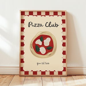 May include: A framed print with a red and cream checkered border. The print features a pizza illustration with the words "Pizza Club" and "8pm til late" in black script. The pizza has red sauce, white cheese, and green basil.