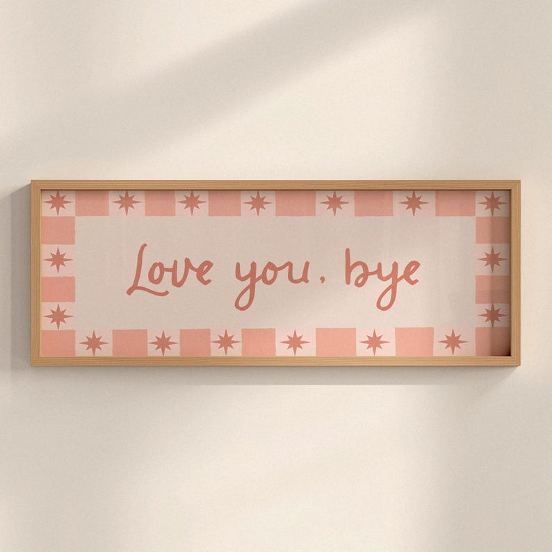 Puede incluir: Una impresi&oacute;n art&iacute;stica rectangular enmarcada en madera con las palabras "Love you. bye" en un estilo manuscrito. La impresi&oacute;n tiene un borde a cuadros rosa claro y blanco con acentos de estrellas.