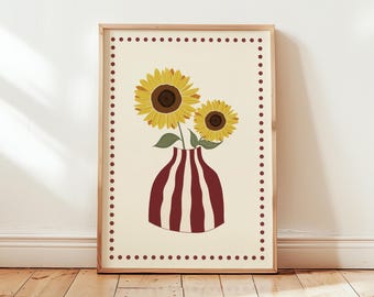May include: A framed art print featuring two sunflowers in a red and white striped vase. The sunflowers have yellow petals and brown centers. The artwork is set against a cream background with a dotted border.