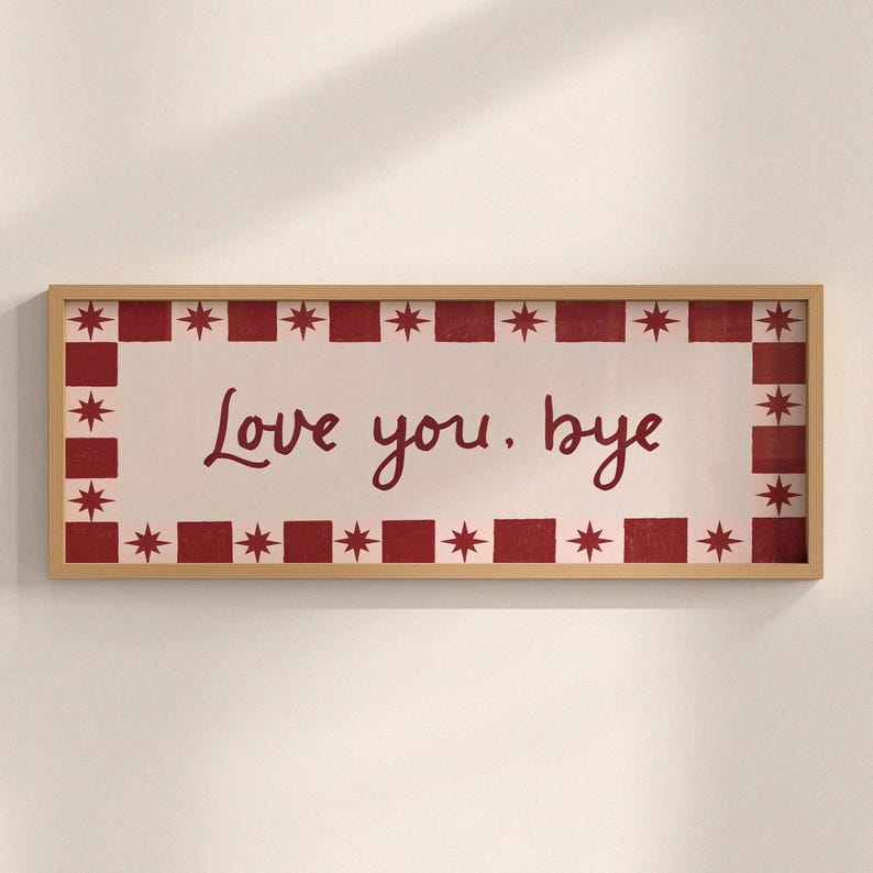 Puede incluir: Un letrero rectangular con marco de madera con las palabras "Love you. bye" en escritura burdeos. El letrero tiene un fondo blanco con un borde burdeos de cuadrados y estrellas alternos.