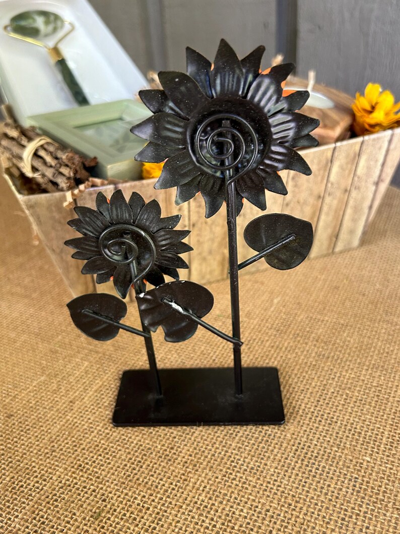May include: Black metal sunflower sculpture with two flowers and leaves on a black metal base.