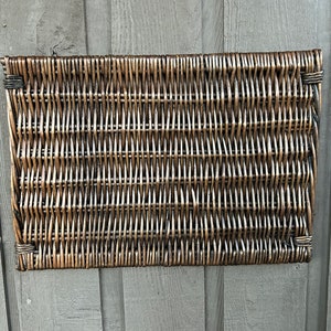 May include: A woven wicker wall hanging with a brown and tan color scheme. The hanging is rectangular and has a woven pattern.