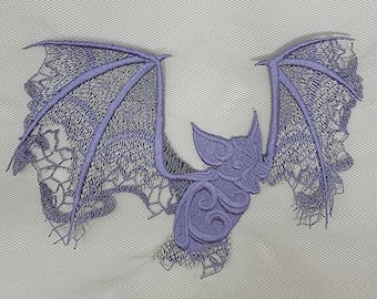 May include: Purple embroidered lace bat applique with intricate details. The bat has outstretched wings and a detailed body.