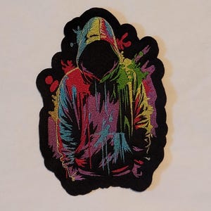 May include: A white ceramic mug with a black handle and the text "But First, Coffee" in a bold, black font. The mug is set against a blurred background, suggesting a cozy setting.