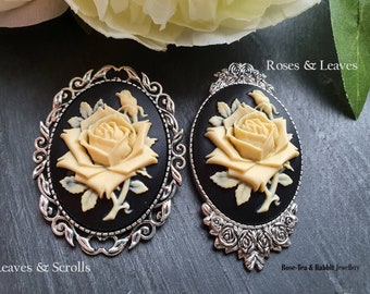 May include: Two oval cameo brooches with cream-colored rose designs on a black background, set in ornate silver-toned frames. The brooches are labeled "Leaves & Scrolls" and "Roses & Leaves". The text "Rose-Tea & Rabbit Jewellery" is also visible.