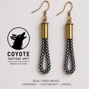 Op de afbeelding: Messing oorbellen met zwart en zilver touwdetail. De oorbellen hebben goudkleurige haken en cilindrische messing accenten. De afbeelding bevat de tekst "COYOTE TACTICAL UNIT BRASS DIVISION" en "REAL FIRED BRASS HANDMADE • LIGHTWEIGHT • UNIQUE."
