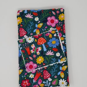 Puede incluir: Un paño de cocina de tela verde con un estampado floral y de setas de colores. El paño de cocina tiene un borde blanco y un paño de cocina a juego más pequeño unido a él.