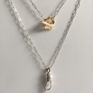May include: Two silver chains with a gold flower clasp and a silver lobster clasp.