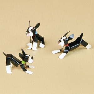May include: Three black and white metal Boston Terrier figurines. The figurines are in different poses, one sitting, one standing, and one running. The figurines are painted with black, white, and red accents.