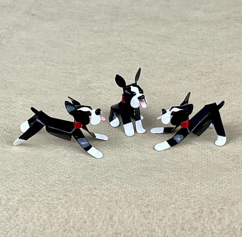 May include: Three black and white Boston Terrier figurines with red collars. The figurines are made of metal and are posed in different positions.