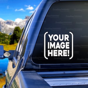 May include: A black pickup truck with a sticker on the back window that says "YOUR IMAGE HERE!" The truck is parked in front of a scenic mountain landscape with a lake in the foreground.