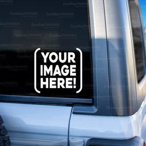 May include: A white Jeep with a black window sticker that says "YOUR IMAGE HERE!" The Jeep is parked in a snowy area with mountains in the background.