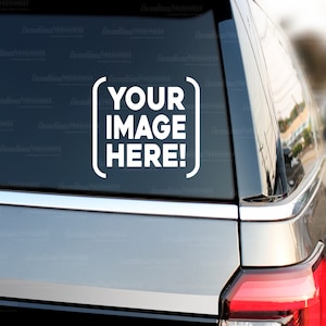 Può includere: Un'auto bianca con un adesivo sul lunotto posteriore che dice "YOUR IMAGE HERE!" in una cornice quadrata.