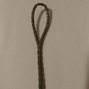 May include: A close-up of a brown braided cord with a loop at the top.