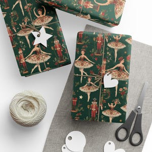 May include: Gift-wrapped presents with a festive green paper featuring illustrations of ballerinas and nutcrackers. Each package is tied with twine and a decorative tag. A ball of twine, scissors, and blank tags are also present.