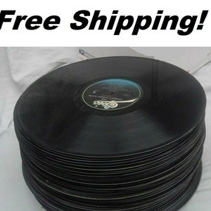 May include: A stack of black vinyl records, approximately 20 records high, with the label of one record visible. The label is white with black text that reads "The Stanley Clarke Band" and "Epic".