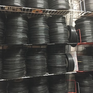 May include: A wall shelf filled with stacks of black vinyl records. The records are organized in rows and columns, creating a visually appealing pattern.