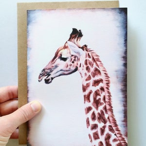 May include: A watercolor painting of a giraffe's head and neck. The giraffe is light brown with darker brown spots. The background is a soft pink and white.