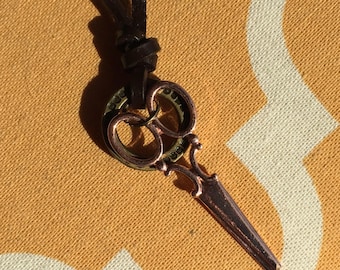 Rose gold scissor charm on an adjustable leather necklace