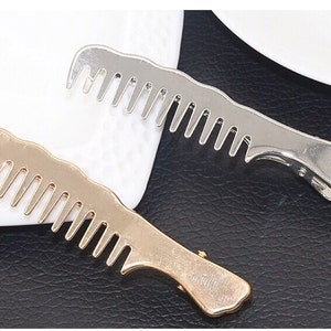 May include: Two hair clips in the shape of combs. One is gold and the other is silver.