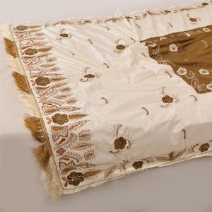 May include: A white silk shawl with brown and gold embroidery and fringe. The shawl has a floral design and is decorated with beads.