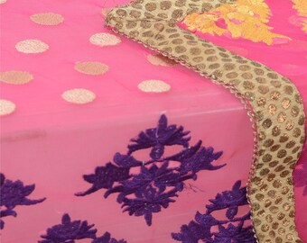 May include: A bright pink sheer fabric featuring a pattern of metallic gold polka dots. The textile is adorned with dark purple floral embroidery and a wide, decorative border in a metallic gold mesh with a repeating circular pattern.