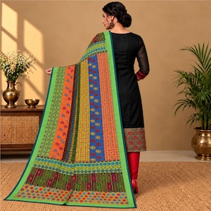 Puede incluir: Una túnica negra de manga larga con un dobladillo estampado, combinada con pantalones rojos y un gran chal rectangular con rayas verticales en naranja, azul y verde con intrincados motivos florales y geométricos y un borde verde brillante.