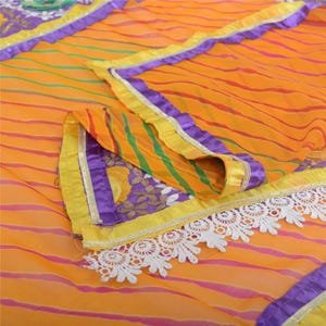 May include: A yellow and orange striped fabric with purple and gold trim. The fabric has a white lace trim and a floral design.