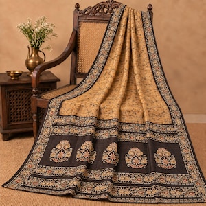 May include: A rectangular textile featuring a tan centre with a dark brown crackle pattern, bordered by a wide dark brown band. The border displays repeating floral motifs in cream, orange, and brown, finished with a thin decorative edge.