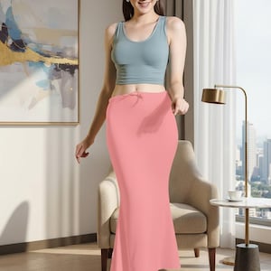 May include: A light blue tank top paired with a coral pink skirt. The skirt has a drawstring waist and a fitted silhouette that flares out at the hem. The outfit is simple and elegant.