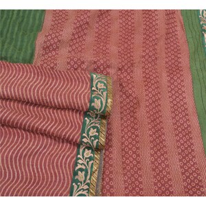 Peut inclure: Un tissu à motifs rouge et vert avec un design ondulé. Le tissu est orné d'une bordure dorée et verte avec des motifs floraux.