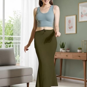 May include: An olive green skirt with a drawstring waist and a slight flare at the hem. The skirt is paired with a light blue tank top. The outfit is simple and elegant, suitable for casual wear.