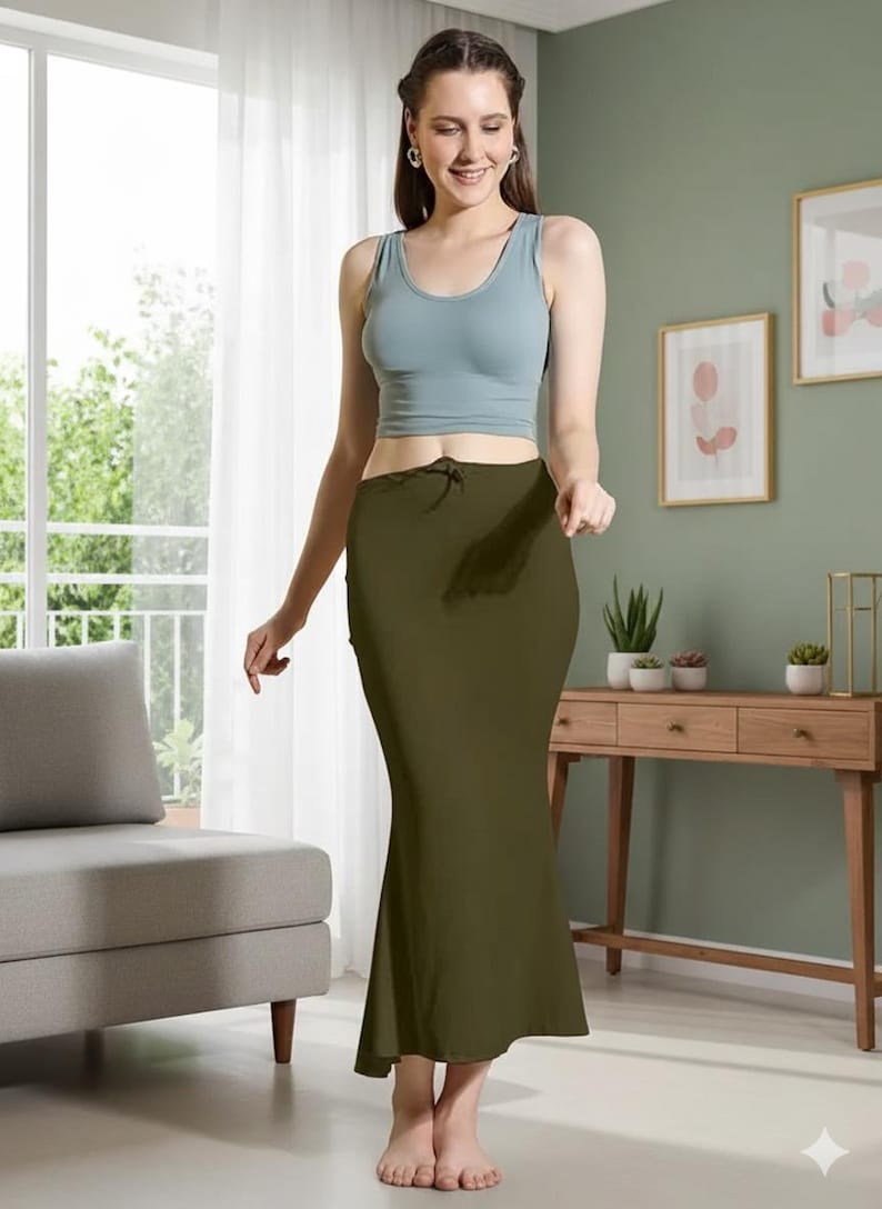May include: An olive green skirt with a drawstring waist and a slight flare at the hem. The skirt is paired with a light blue tank top. The outfit is simple and elegant, suitable for casual wear.
