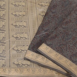 May include: A grey and brown silk saree with a paisley pattern and a gold border. The saree features a traditional Indian design with intricate details.