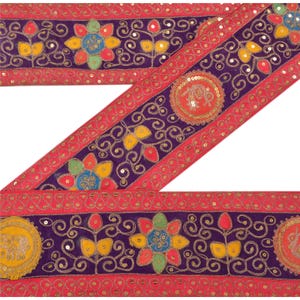 May include: Decorative trim with a vibrant design. The trim features a deep purple center with floral and swirl patterns in yellow, red, blue, and green. The edges are a bright red, and the design is embellished with gold sequins.