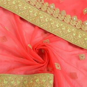 May include: A sheer coral fabric textile featuring a wide border with intricate gold embroidery and small embedded mirrors. The fabric is adorned with scattered square-shaped gold embroidered motifs and additional mirror accents throughout the material.