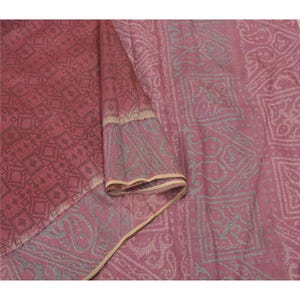 Könnte beinhalten: Ein Textilstoff in einer Farbpalette aus tiefem Rosa und Mauve. Ein Abschnitt zeigt ein dunkles geometrisches Rautenmuster, während der andere Abschnitt ein helleres, komplexes Paisley- und Quadratmotiv mit einem beigen Rand aufweist.