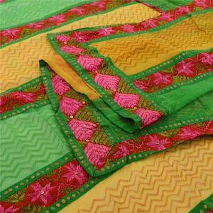 Peut inclure: Un textile vibrant avec des tons verts, jaunes et roses. Le tissu présente un motif en zigzag et est orné de broderies florales détaillées le long des bordures. Le design intègre un mélange de couleurs et de textures, créant une esthétique visuellement attrayante.