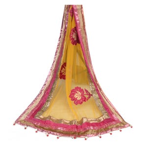 May include: A sheer yellow scarf with a floral design in shades of pink and red. The scarf is trimmed with gold and pink borders, and small red beads hang from the bottom edge. This accessory is suitable for special occasions.