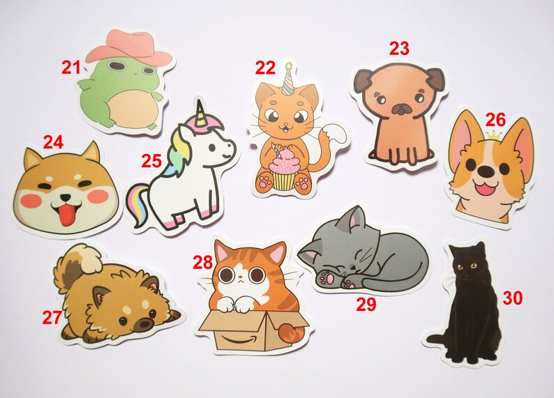 May include: A set of ten colorful cartoon animal stickers. The stickers feature a frog wearing a cowboy hat, a unicorn, a cat with a birthday hat, a pug, a corgi, a Shiba Inu, a cat in a box, a sleeping cat, a black cat, and a fluffy dog.