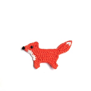Op de afbeelding: Een gehaakte vossenapplicatie in fel oranje met witte en zwarte accenten. De vos heeft een witte borst en staartpunt, en zwarte ogen en neus. Dit handgemaakte item is ideaal voor kleding of accessoires.
