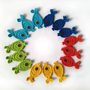 May include: A set of crocheted fish ornaments in various colors, including blue, green, yellow, and red. The fish are arranged in a circle, with their tails pointing outwards.