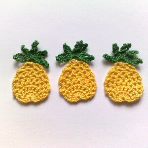 Op de afbeelding: Drie gebreide ananas-versieringen in geel en groen. De ananas zijn gemaakt met een textuur-steek en hebben een realistische vorm.