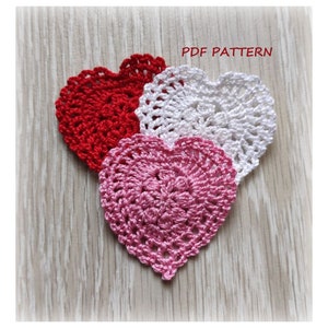 May include: Three crocheted hearts in red, white, and pink. The hearts are layered on top of each other. The image includes the text "PDF PATTERN".